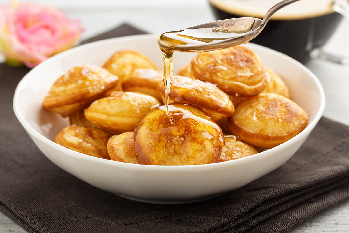 Stockfoto - Poffertjes - Minipfannkuchen mit Puderzucker und Honig